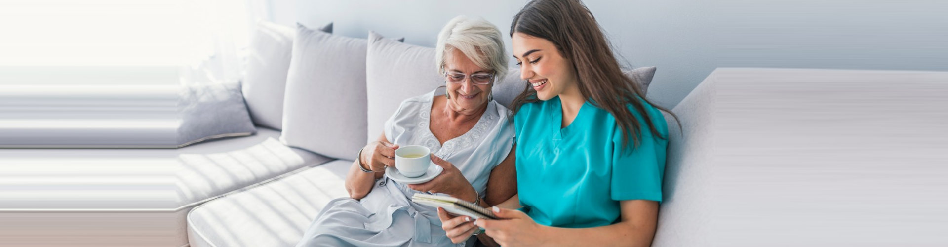 caregiver and senior woman smiling sitting on the sofa