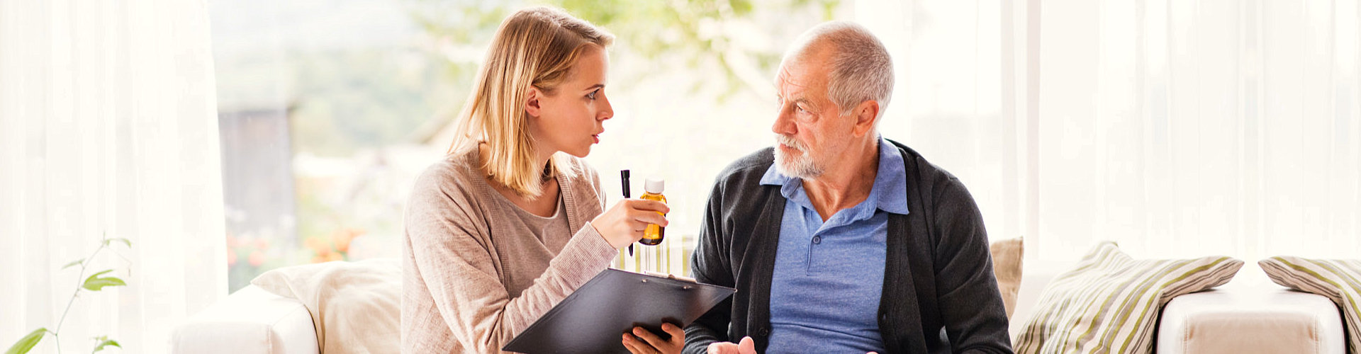 caregiver giving medicine to senior man